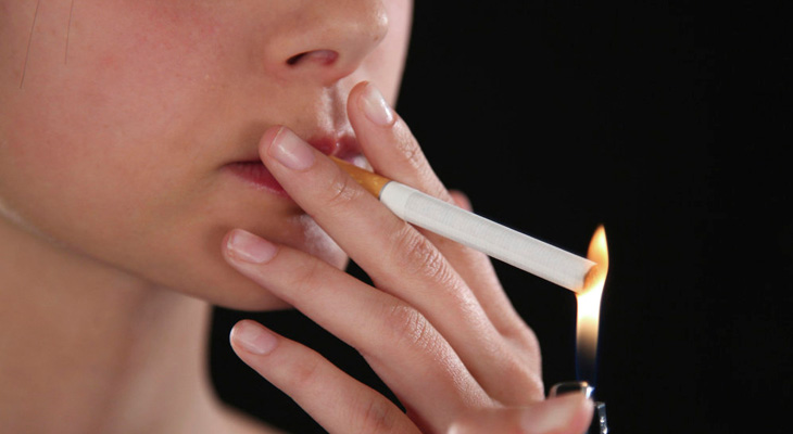 Женщина подкуривает сигарету
